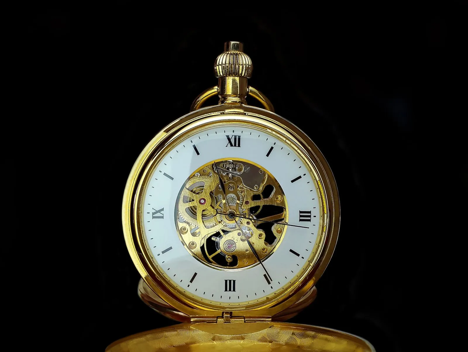 Silver skeleton-dial pocket watch standing on black, its exposed gears a reminder to weigh functions when picking a first Rolex