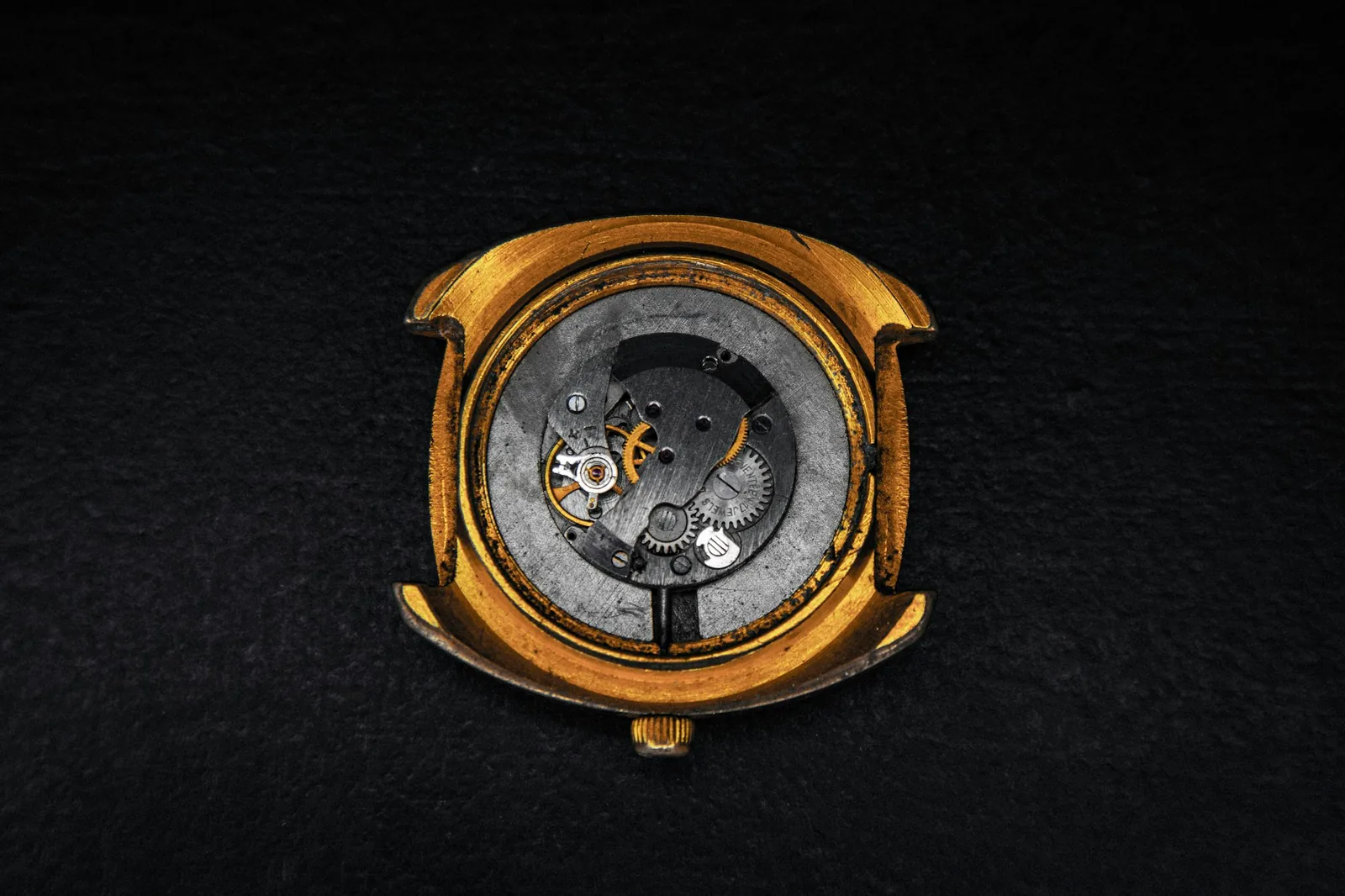 Watch case with the caseback removed showing the movement on dark felt, as a watchmaker checks if a Rolex is real