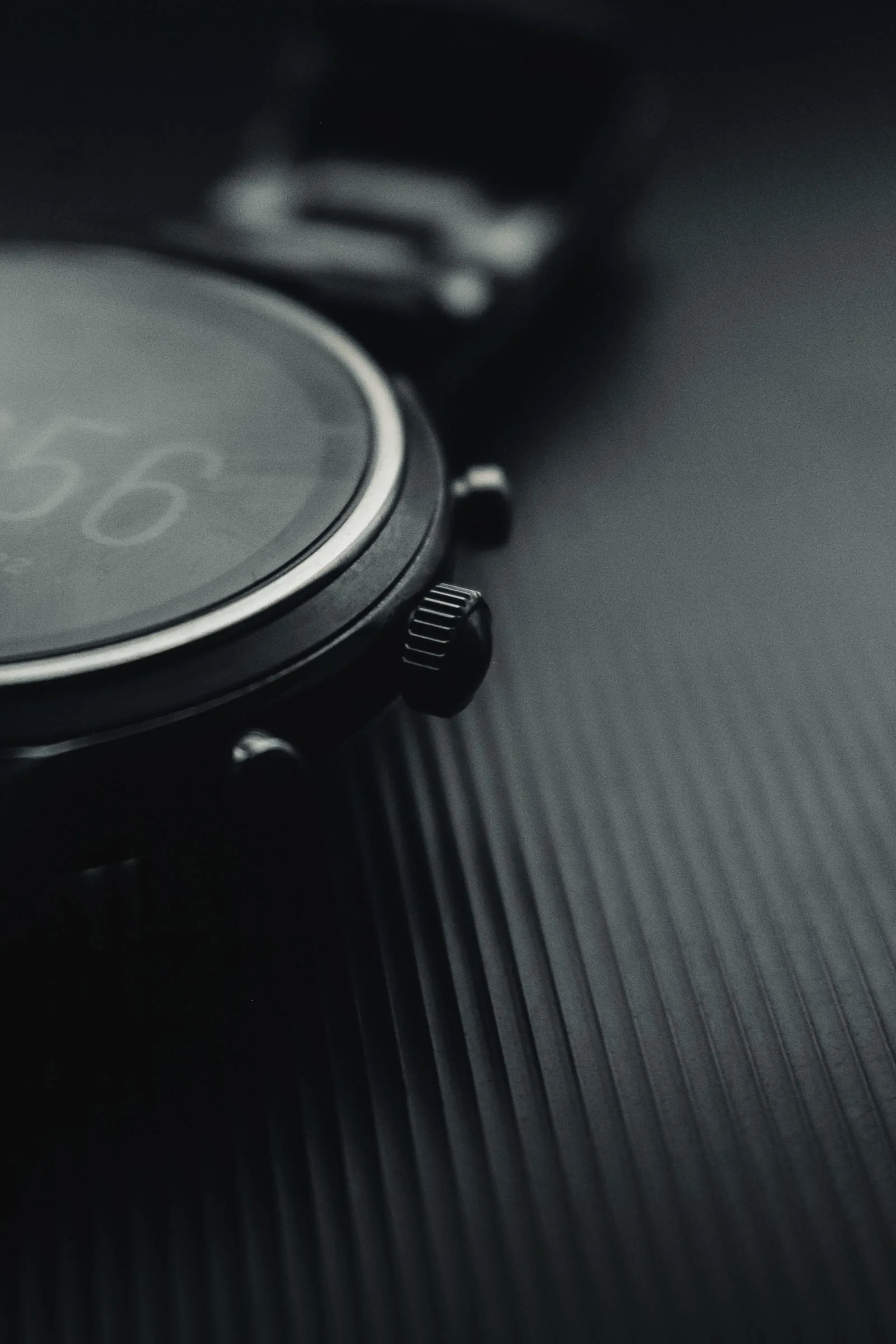 Macro of a black watch crown and pusher beside a dark dial; illustrating how to spot a fake watch