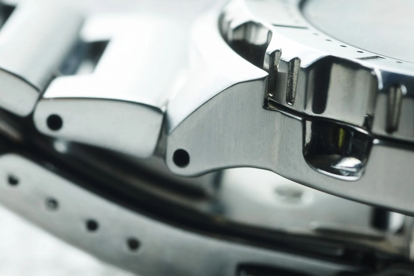 Macro of a steel bezel, lug and bracelet link, the edges to study to tell if a watch has been polished