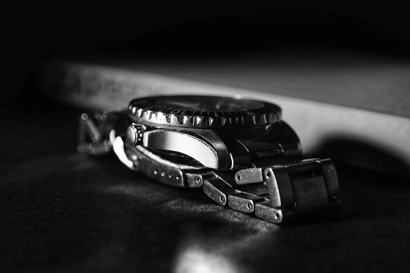 Steel watch on its side showing crown, bezel and bracelet links, the profile view that shows if a watch has been polished