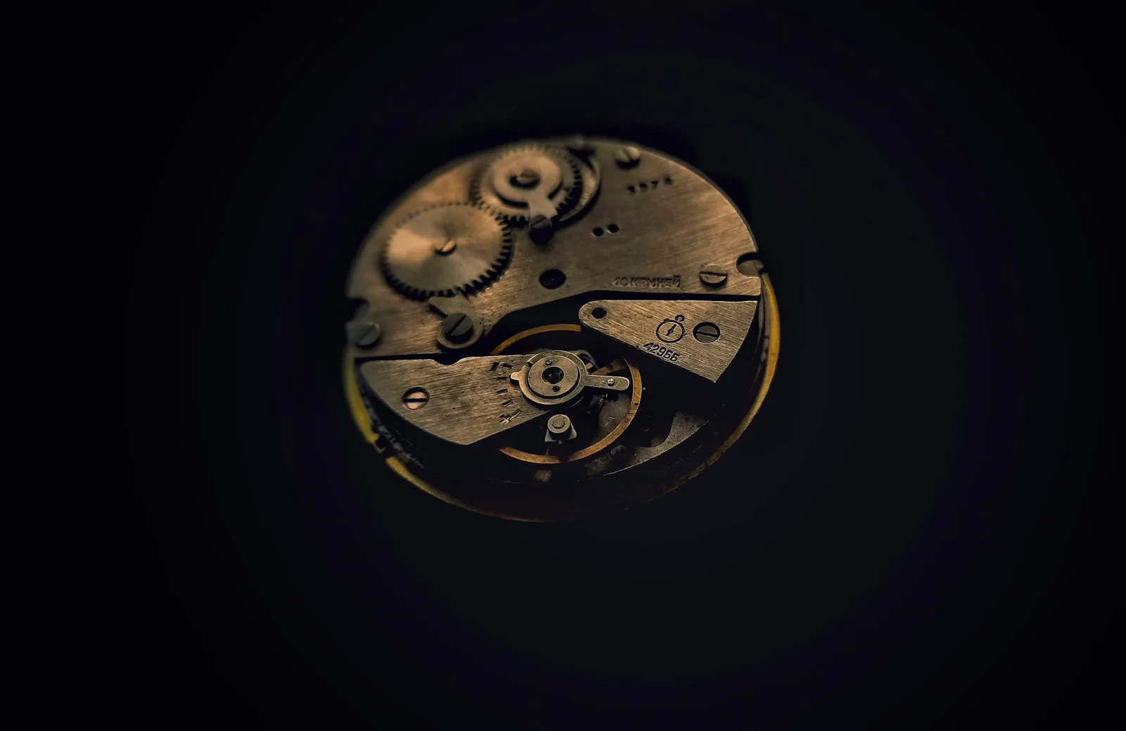 Exposed mechanical watch movement lit against near-black, as found in both in-house and outsourced movement watches