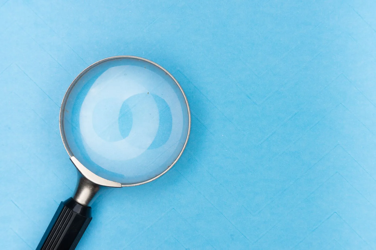 Magnifying glass lying on a plain pale surface; illustrating check if watch is stolen uk
