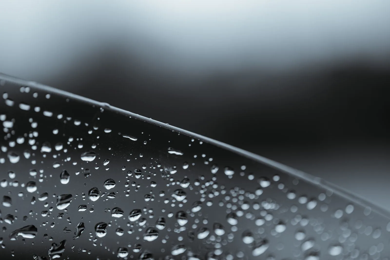 Water droplets along a dark curved surface, a reminder to check water resistance on Submariner alternatives