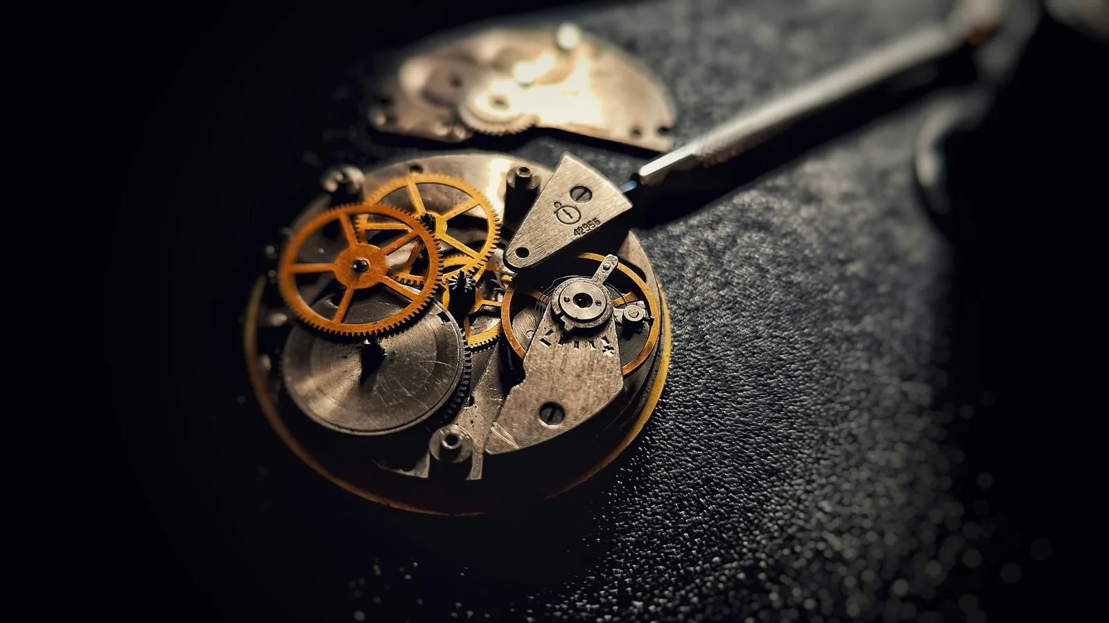 Open watch movement on a dark mat beside a screwdriver, the mechanical choice when deciding how to buy a luxury watch
