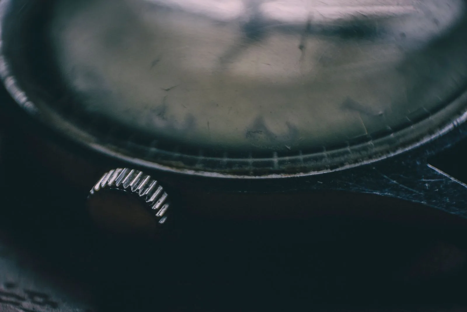 Macro of a worn watch crown and bezel in low light, the kind of wear watch condition grades describe