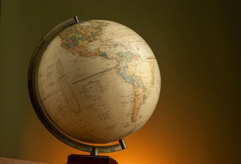 Vintage globe on a stand against a dark grey wall
