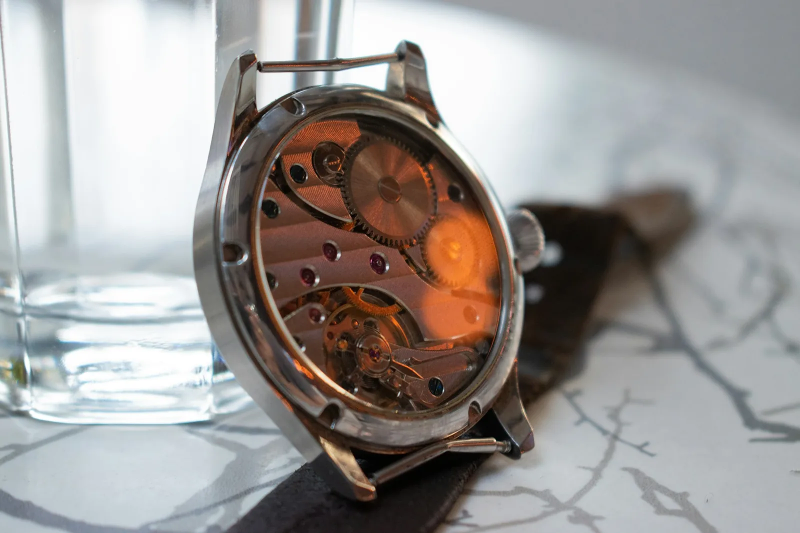Watch seen from behind through a glass caseback showing the gears, where some watch serial numbers are engraved
