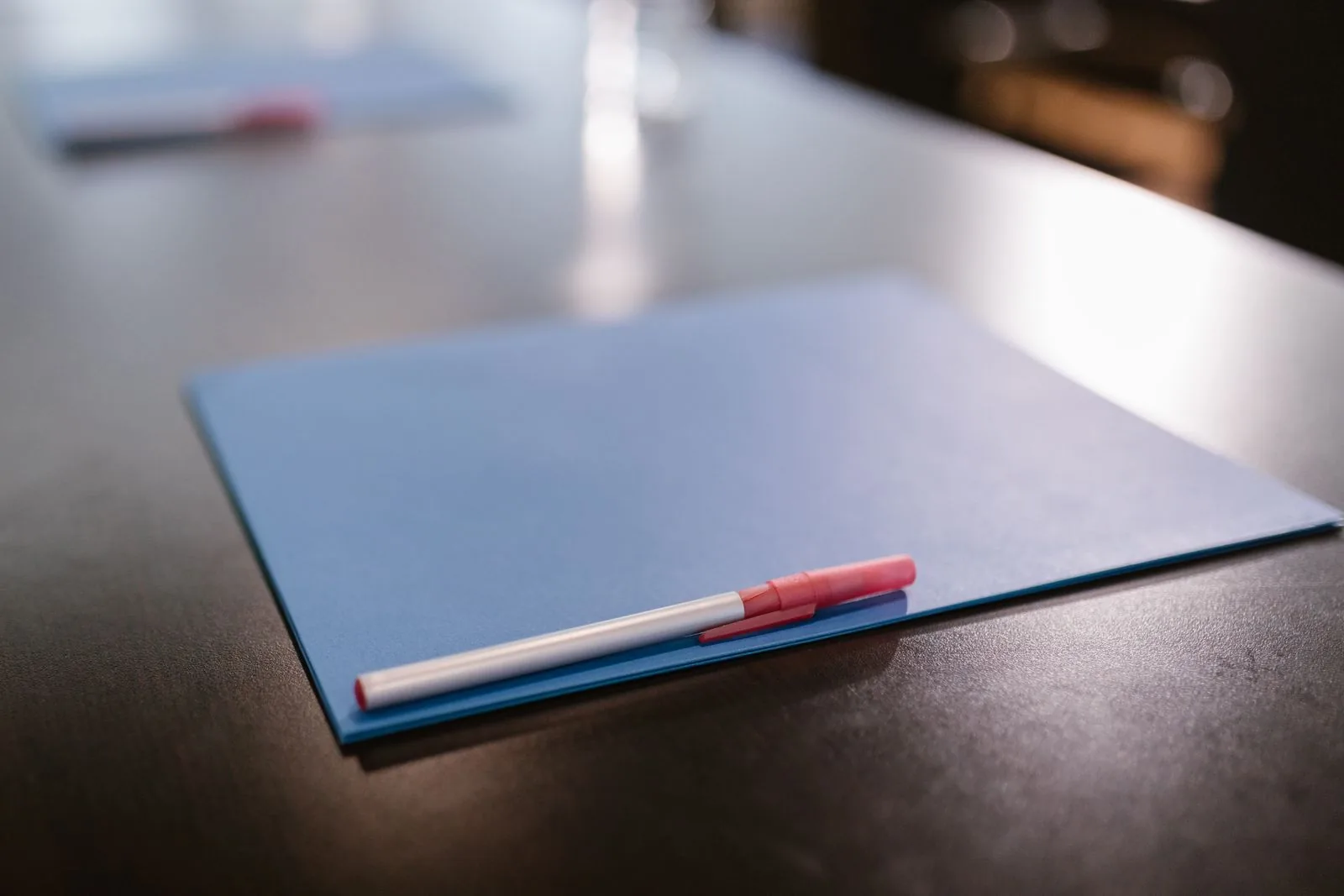 Closed grey folder with a pen on a dark desk; the paperwork behind a watch warranty
