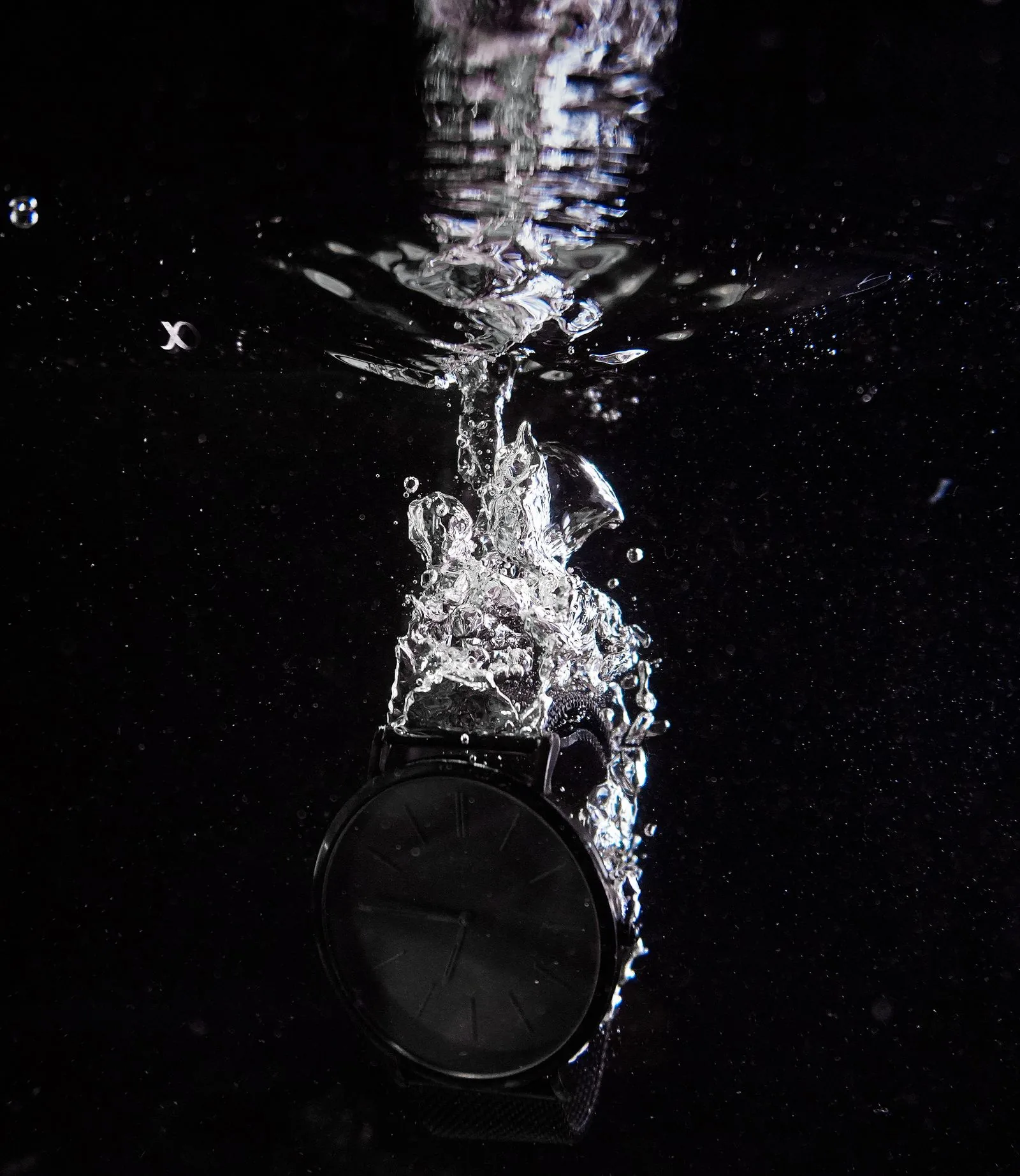 Black watch plunging into water against a black background, the conditions watch water resistance ratings are tested for