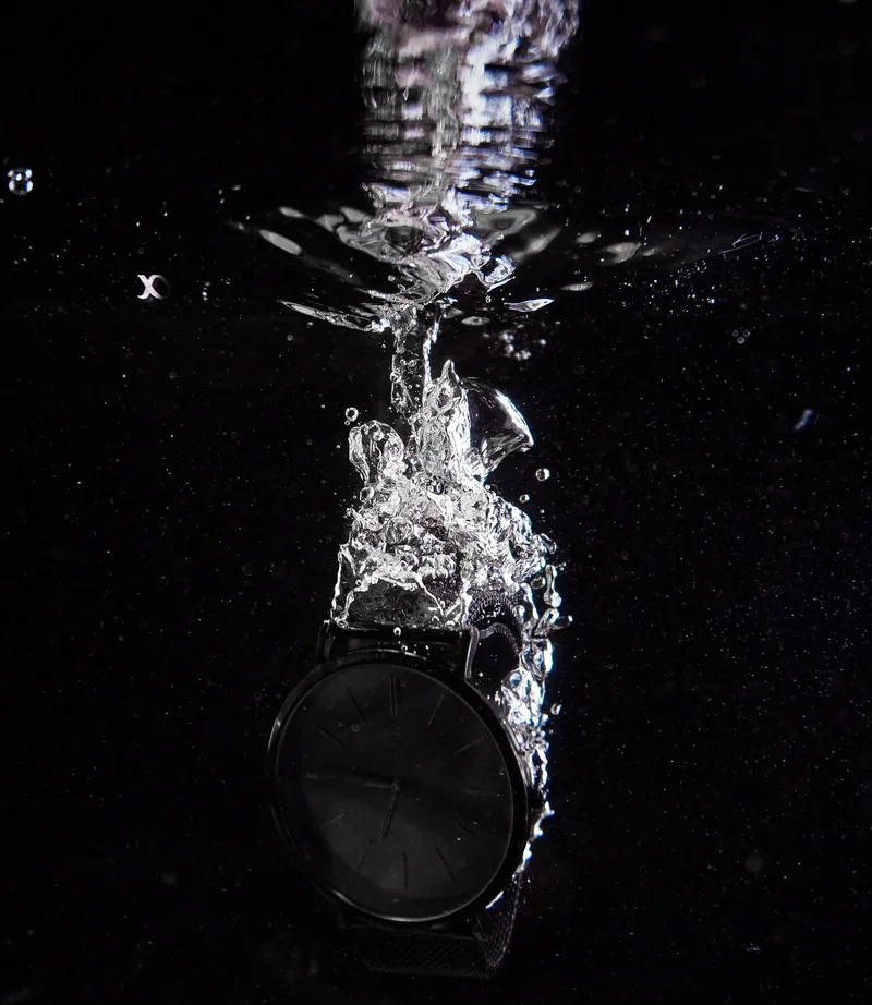 Black watch plunging into water against a black background