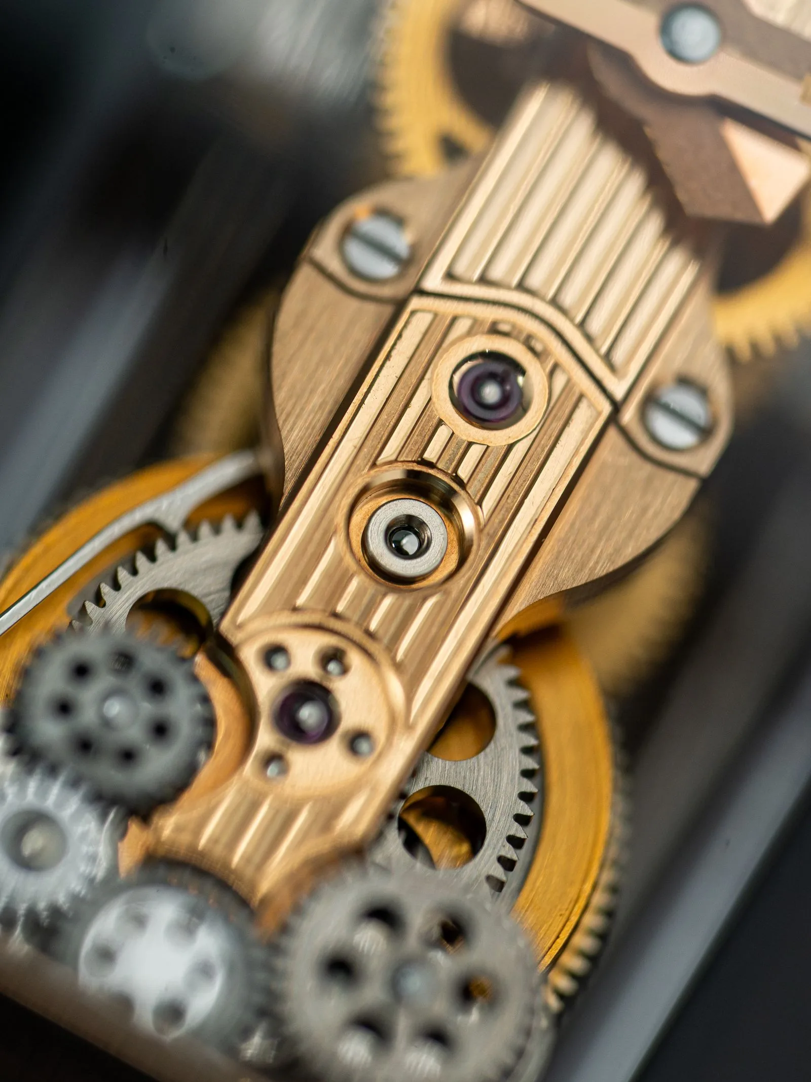 Macro of a polished bridge and gear train; a watchmaker can check the movement in a homage watch before you buy